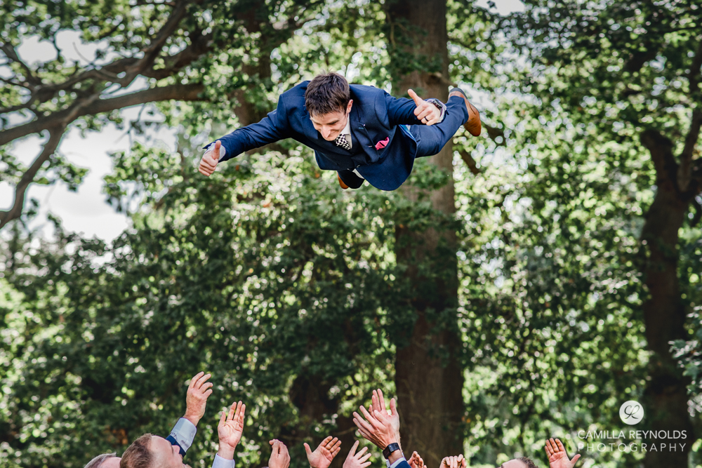 groom thrown in the air by groomsmen fun wedding photography cotswolds