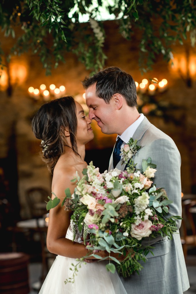 bride groom under flower wheel cotswold barn wedding