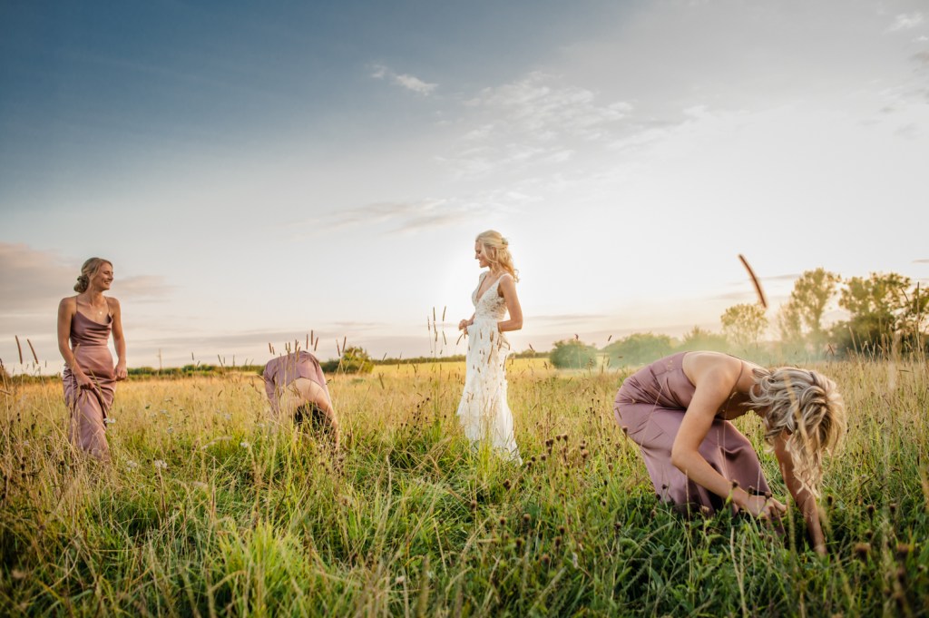 bride and bridesmaids in a field fun  wedding photography