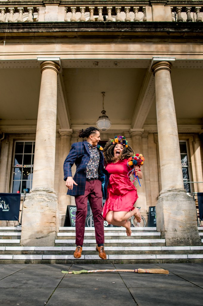 bride and groom jumping over broom cotswold wedding