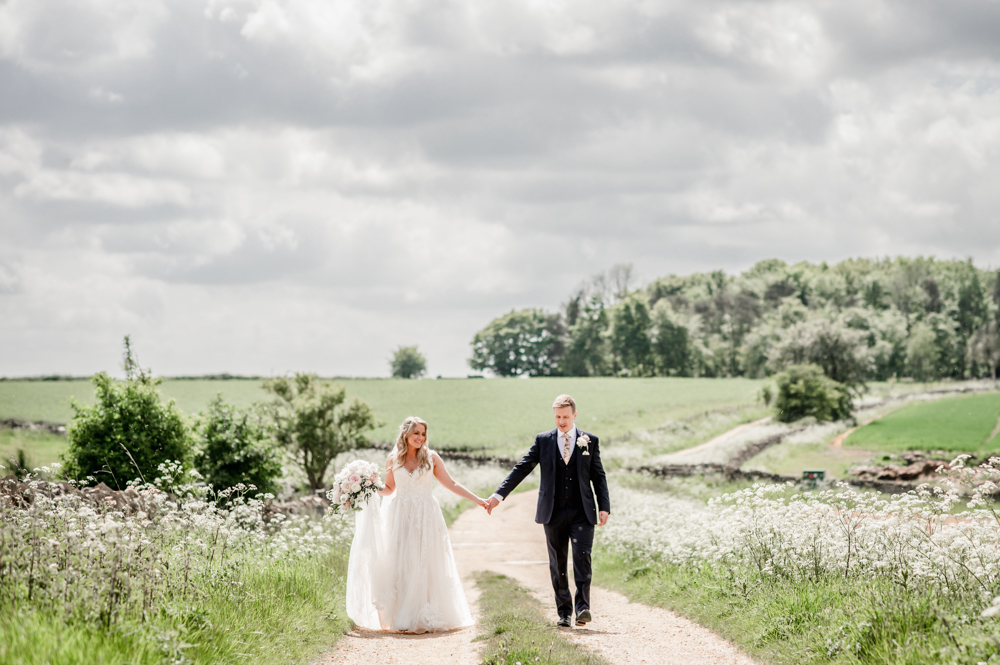 bride and groom walking country road