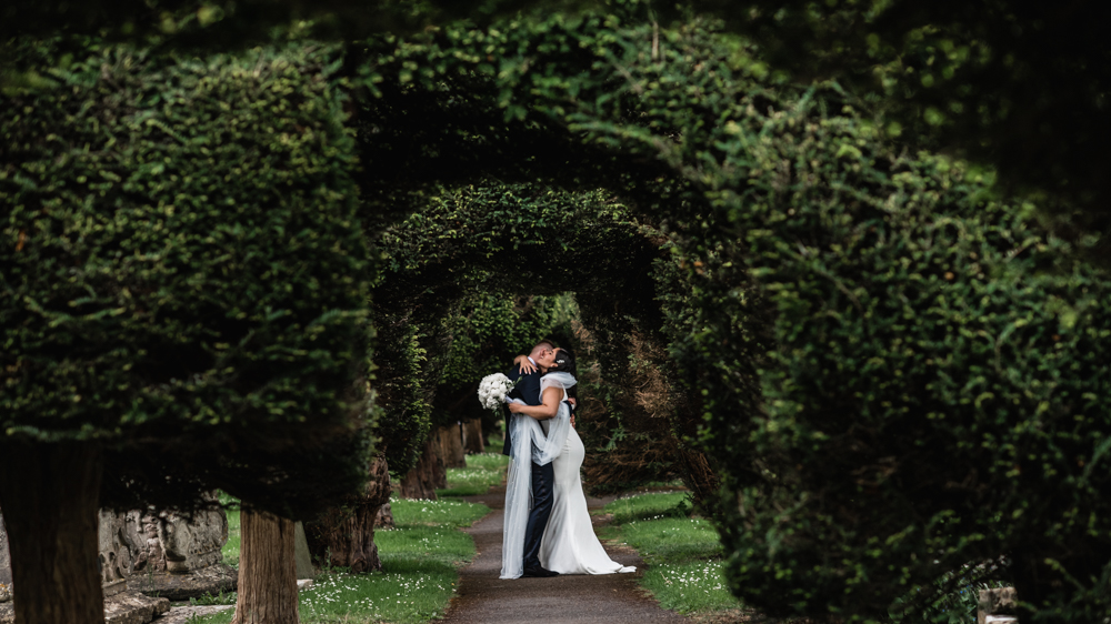 bride groom hugging churchyard england