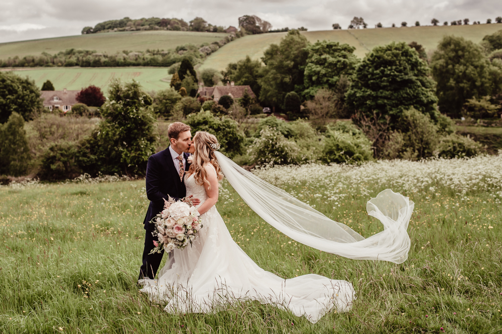 bride and groom kissing in a meadow  romantic