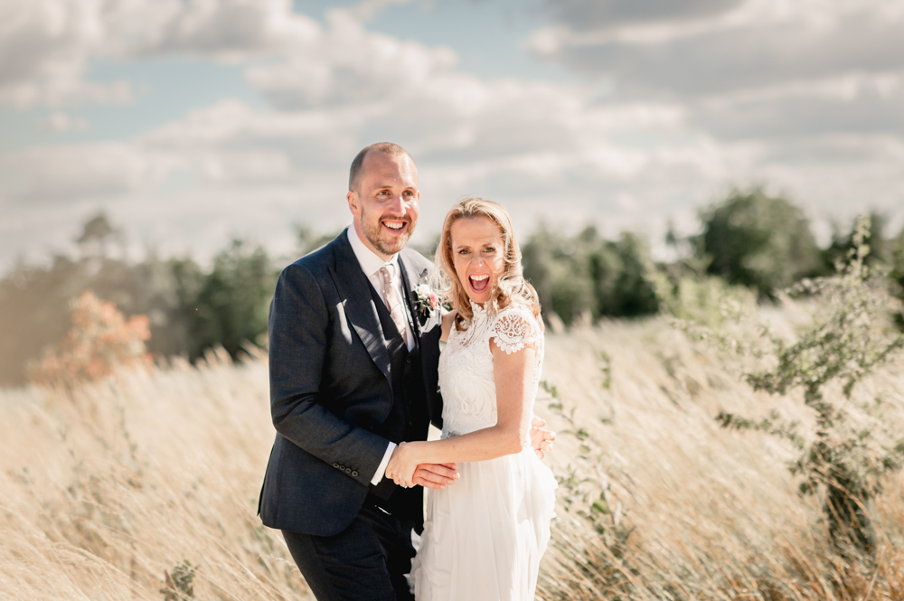 bride and groom laughing in a field