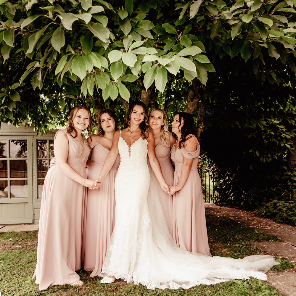 bride and bridesmaids hugging linking arms cotswolds