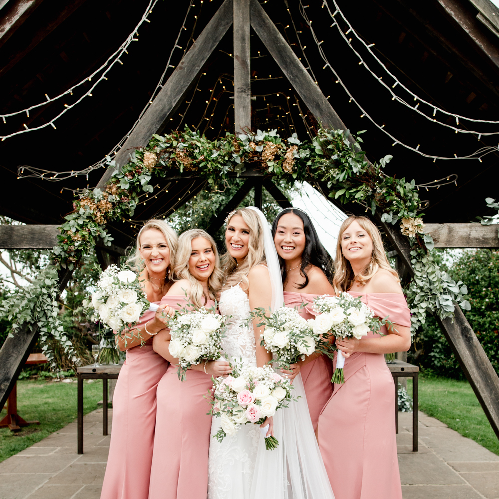 bride and bridesmaids hugging old lodge
