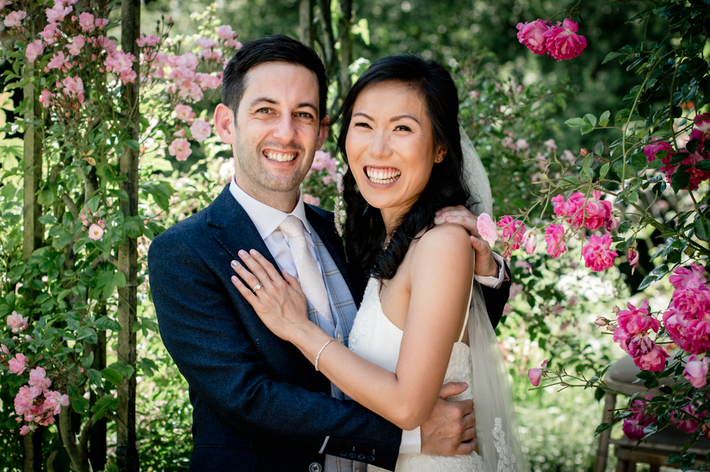 bride and groom under rose arch