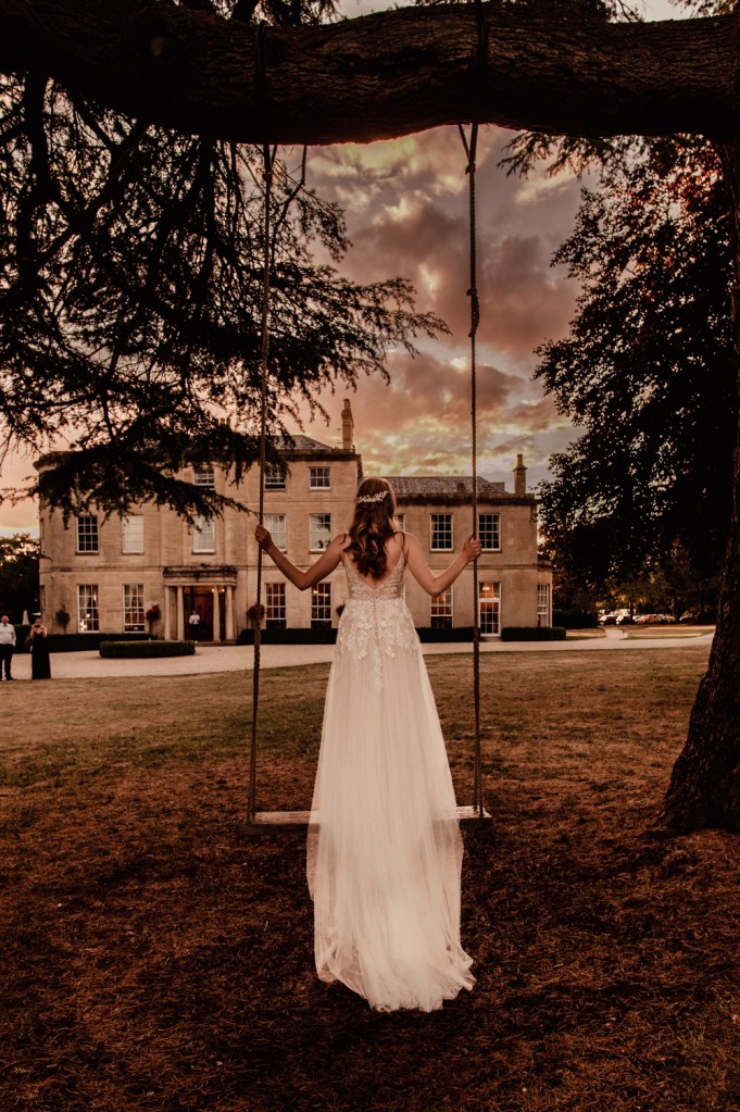 bride on swing dramatic sky cotswold wedding