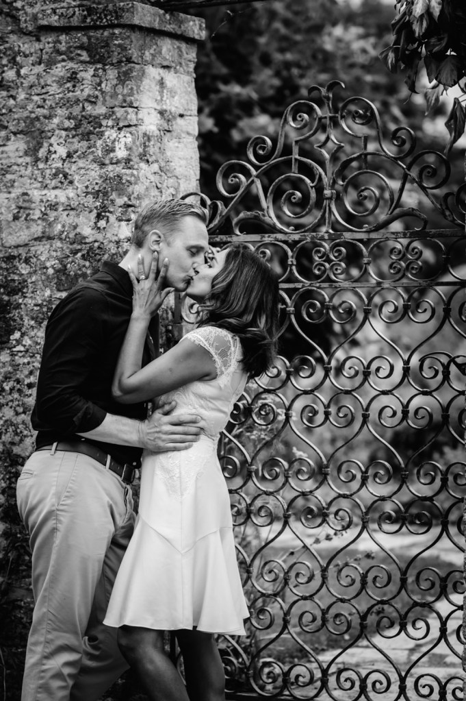 couple kissing next to iron gate