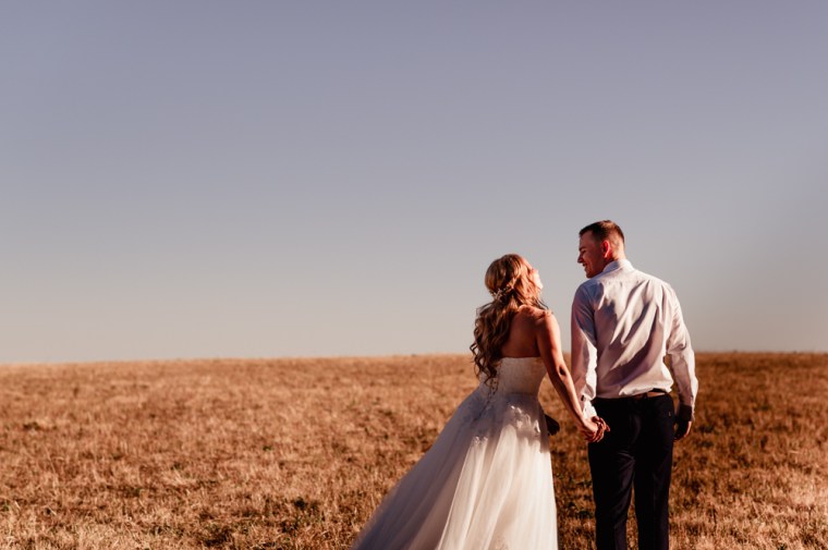 bride and groom walking in the field