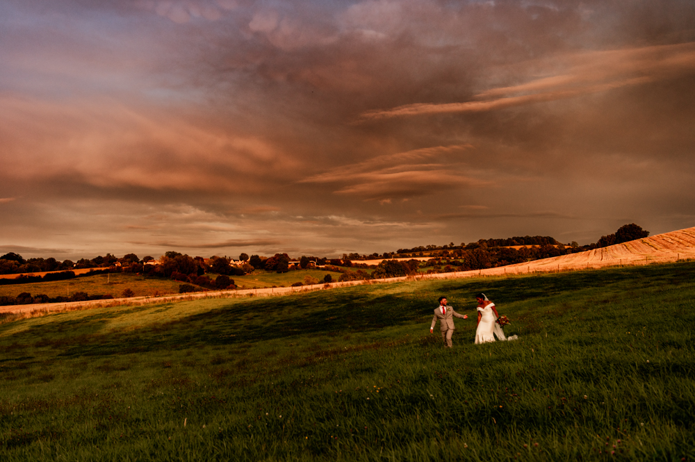 bride and groom walking in field landscape