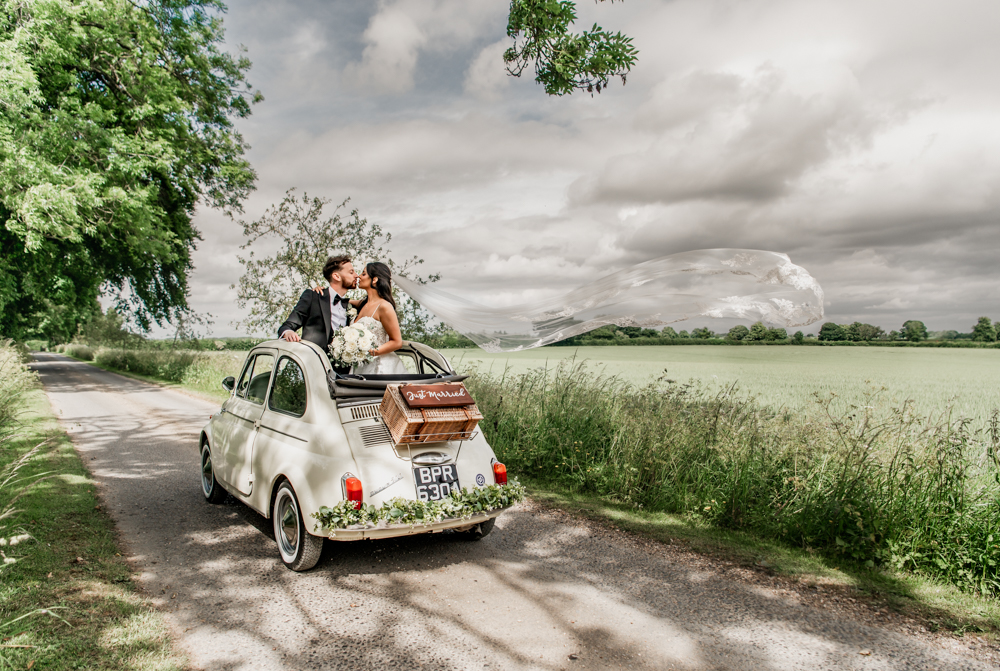 bride and groom in open top wedding car