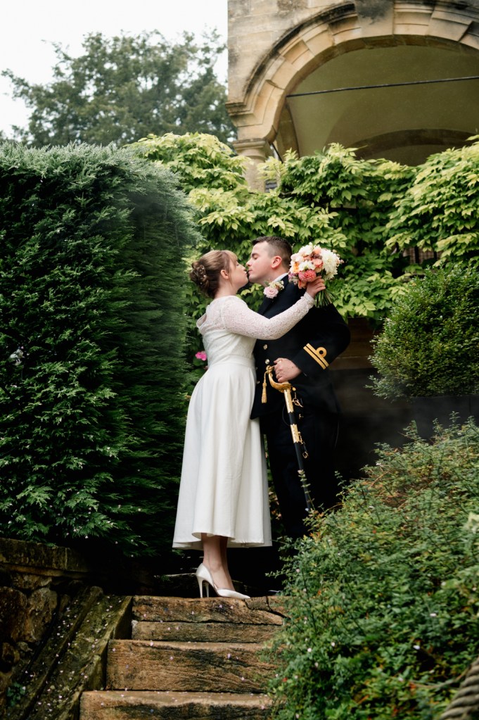 bride and groom kissing under arch