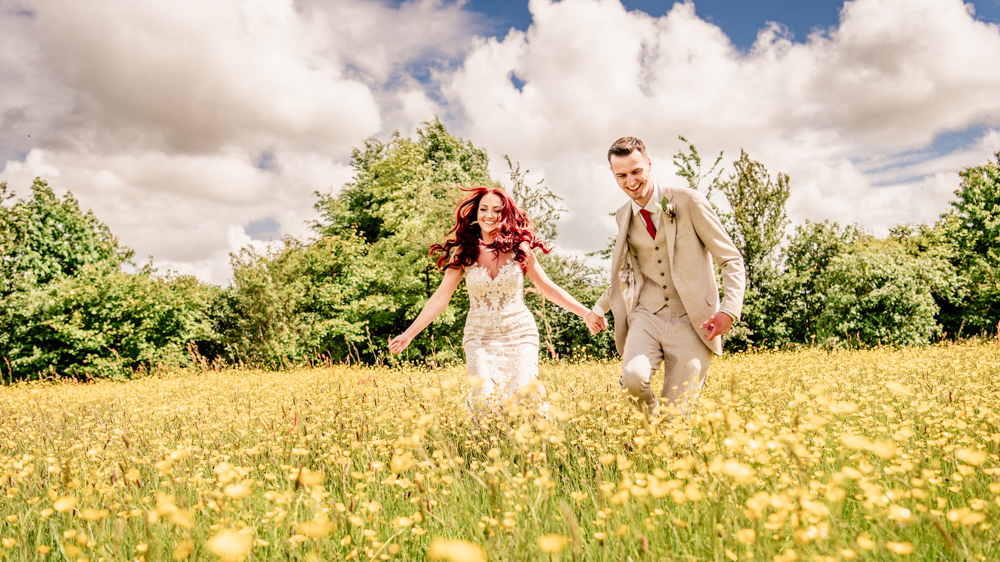 bride and groom running through a flower meadow