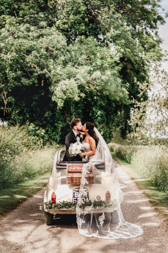 bride and groom in open top wedding car