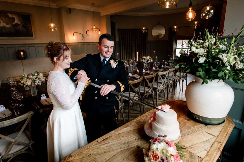 bride and groom cutting wedding cake with a sword