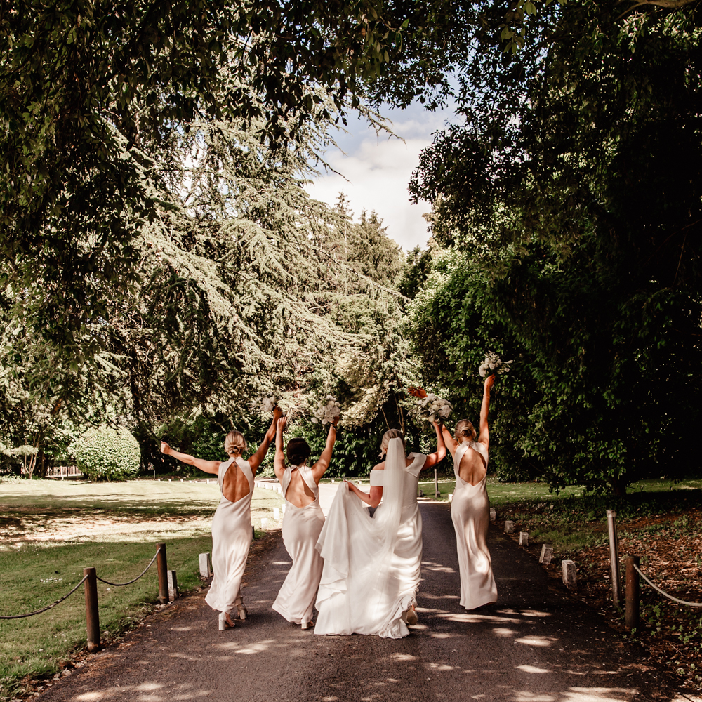 bride walking with bridesmaids running woods
