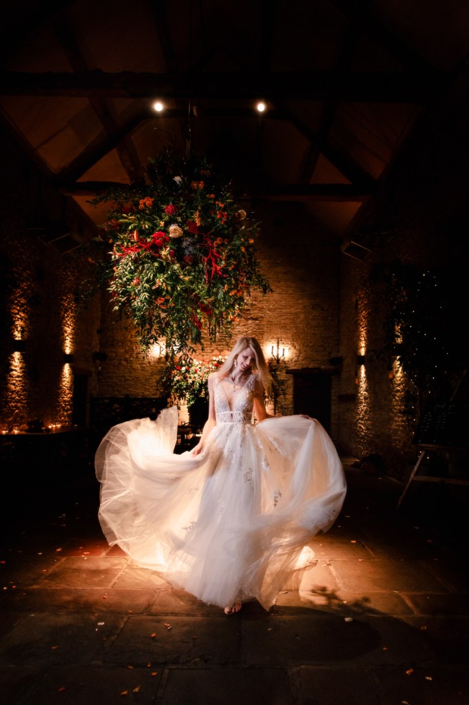 bride walking under floral basket stunning barn wedding