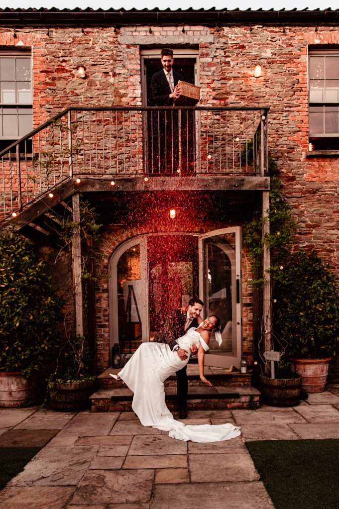 bride and groom kissing under a shower of confetti cotswolds