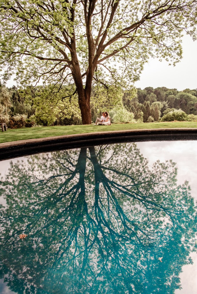 a couple hugging under a tree reflections in the water  cotswold engagement