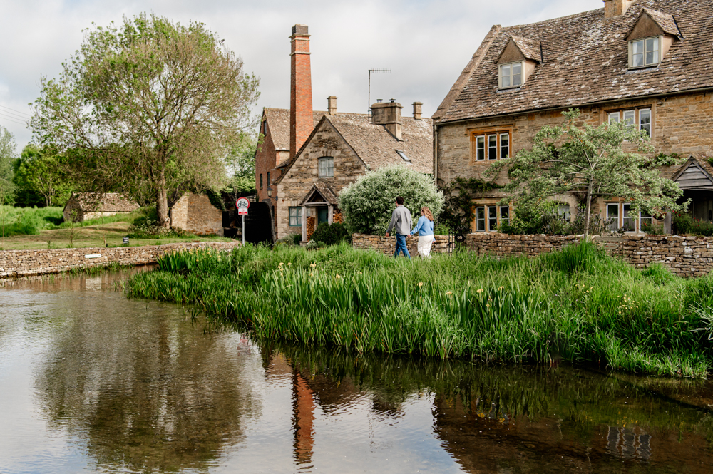 couple walking by water mill cotswolds
