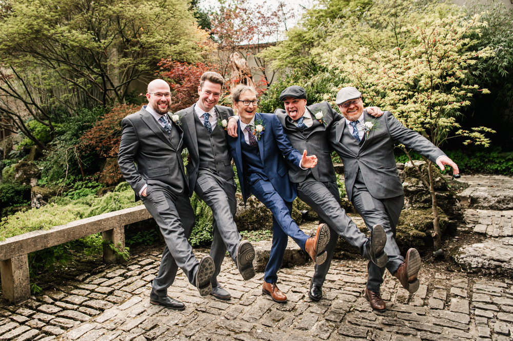 groom and groomsmen silly shots lifting legs 