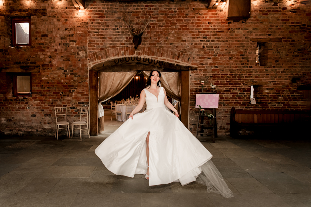 bride twirling in a princess wedding dress with a slit in a luxury rustic  barn venue