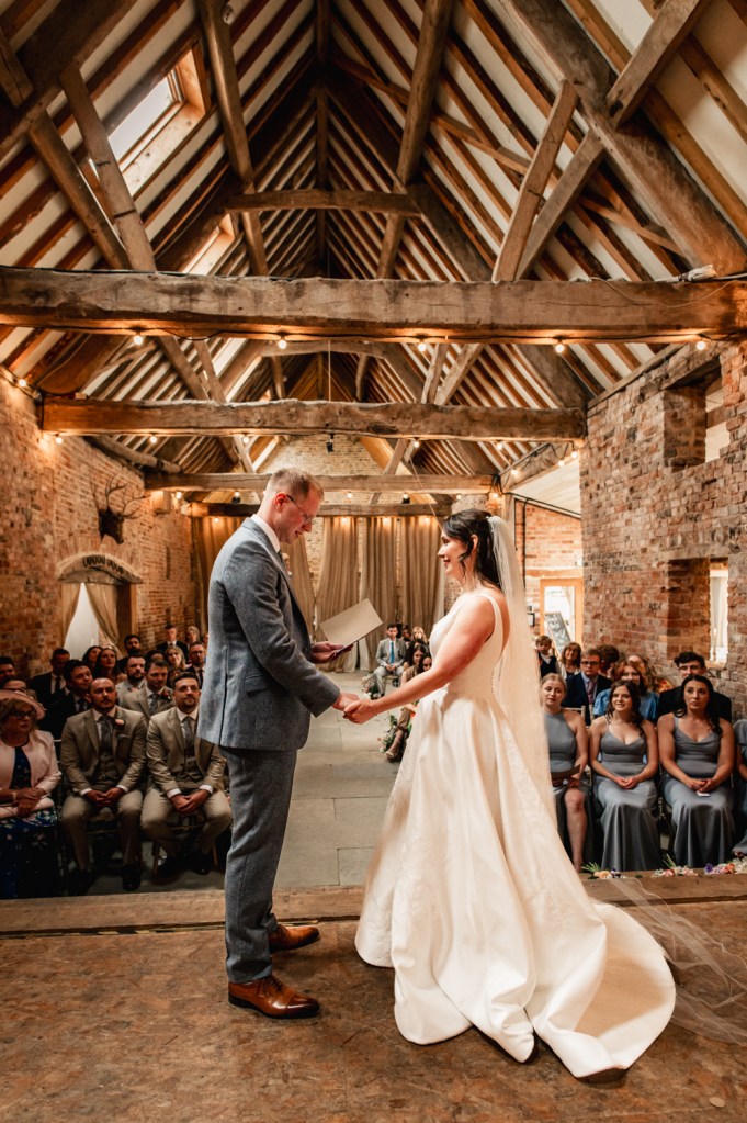 bride and groom exchanging vows barn wedding at Milton End farm