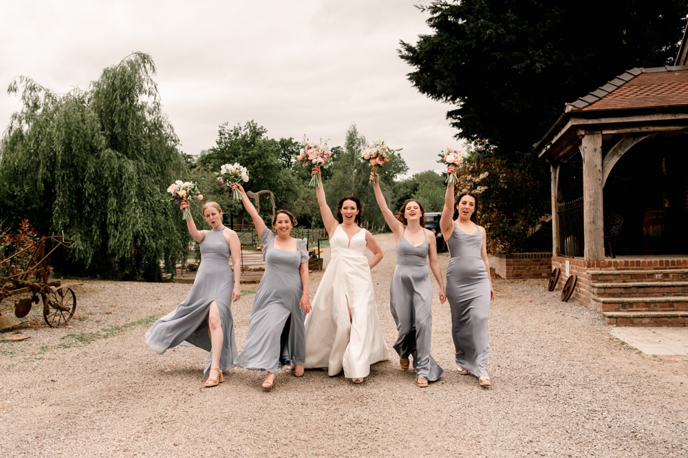 soft photo in pastel tones of bride and bridesmaids walking on a cotswold farm 