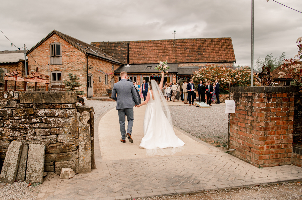 bride and groom walking toward a wedding barn outdoor venue milton end barn