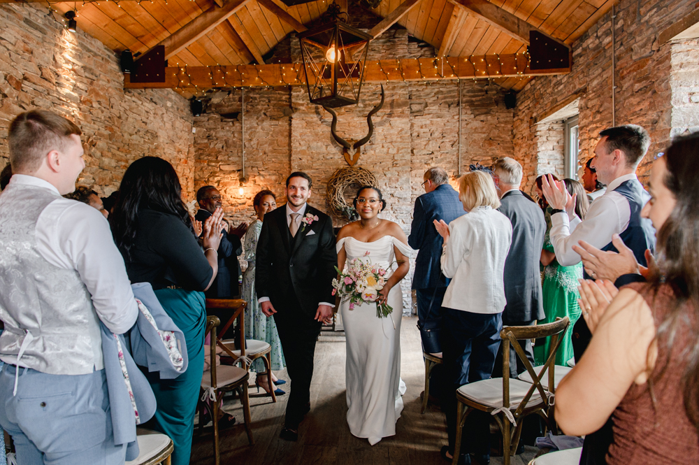 exit of of bride and groom in a rustic barn uk