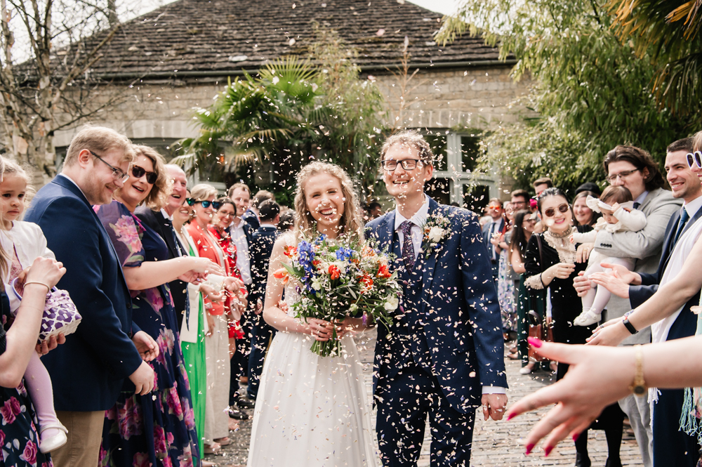 bride and groom laughing confetti toss