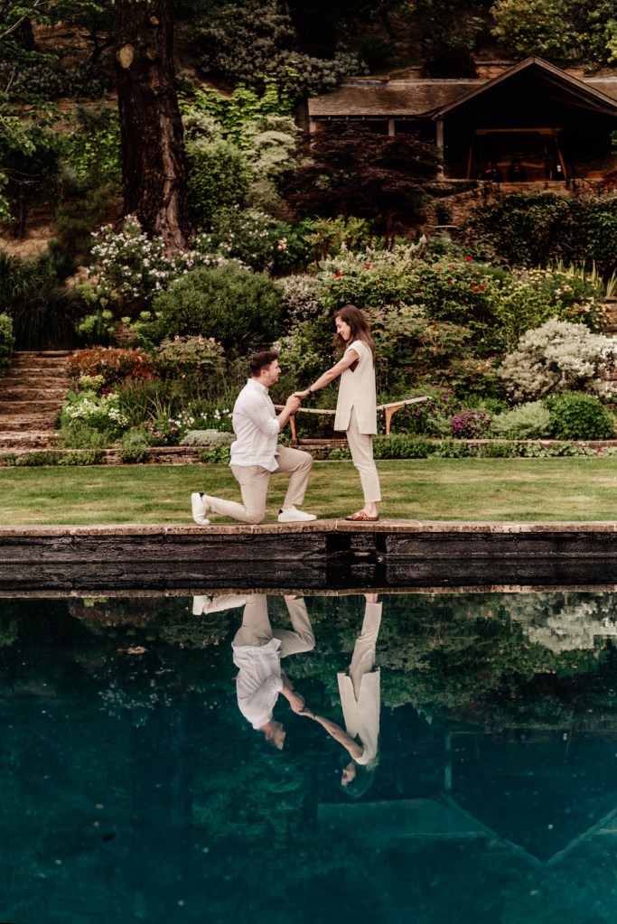 a candid moment of a couple getting engaged in a lush garden 