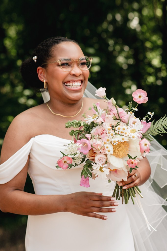 bride smiling holding a colourful summer meadow bouquet