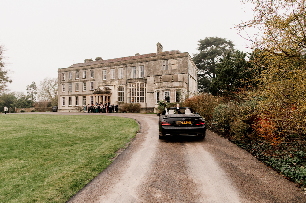 bride and groom driving to elmore court in open top car