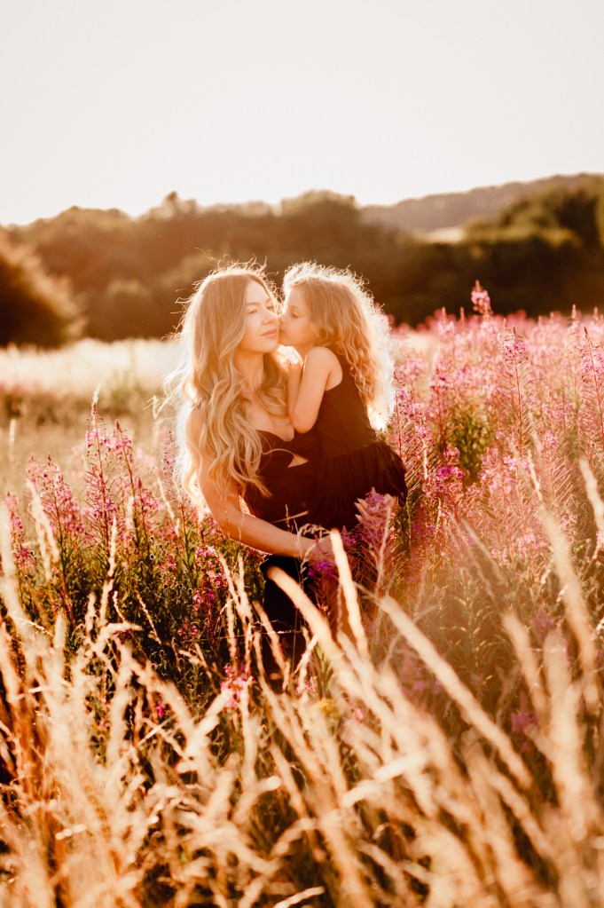 mother and daughter kiss in a field
