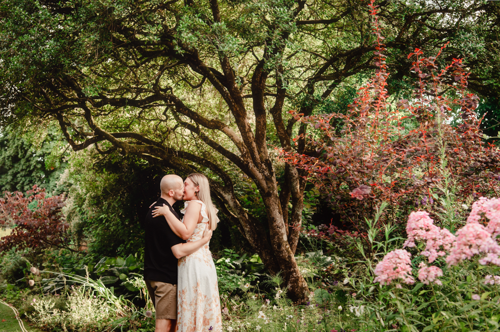 couple kissing in a stunning garden coin the cotswolds