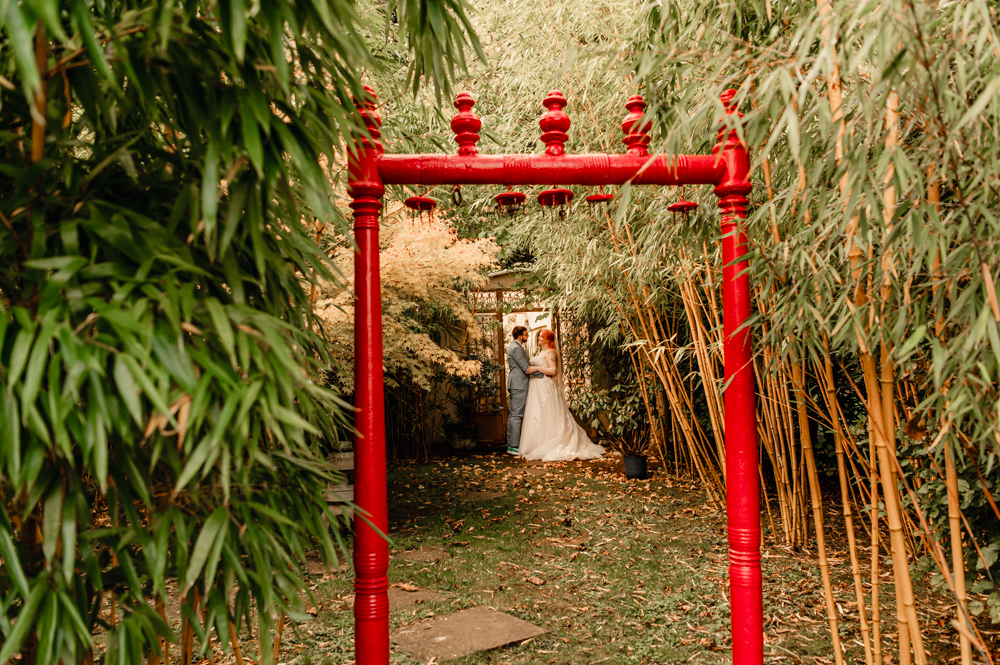bride and groom framed by an asian arch uk