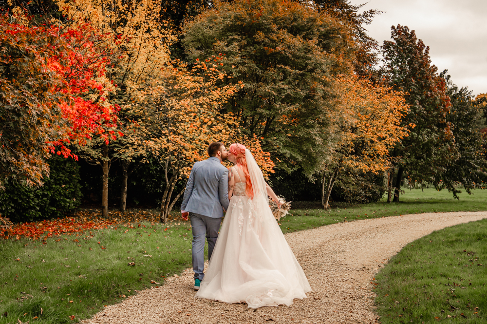 bride and groom kissing walking along path at  at Matara centre cotswolds
