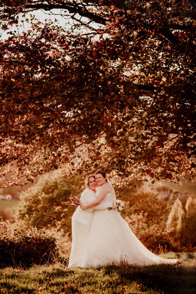 two brides hugging colourful autumn wedding cotswolds