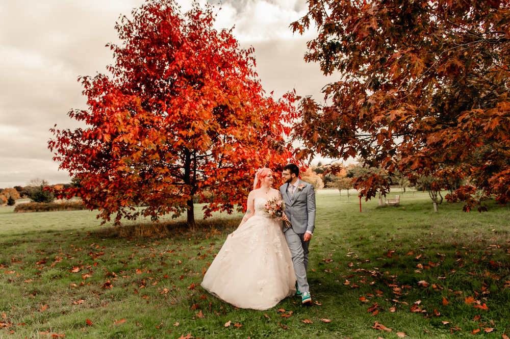 bride and groom walking in a red autumn wood