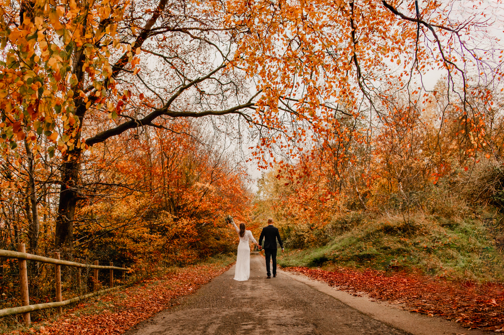 bride and groom walking on  autumn country road