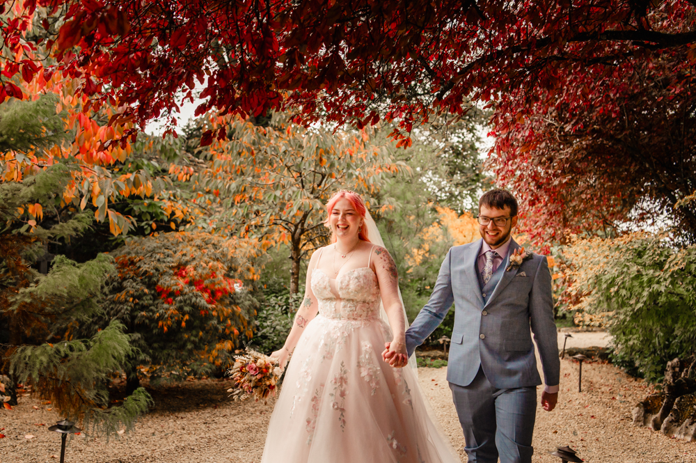 bride and groom walking in a colourful autumn wood cotswolds