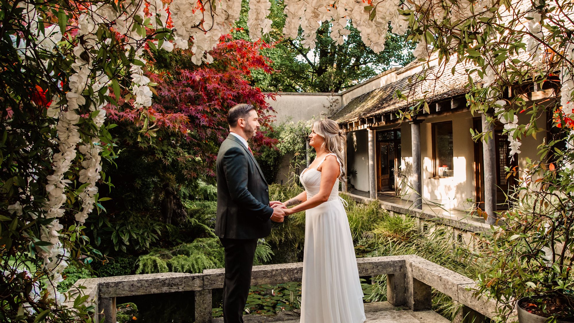 bride and groom holding hands in a lush floral courtyard