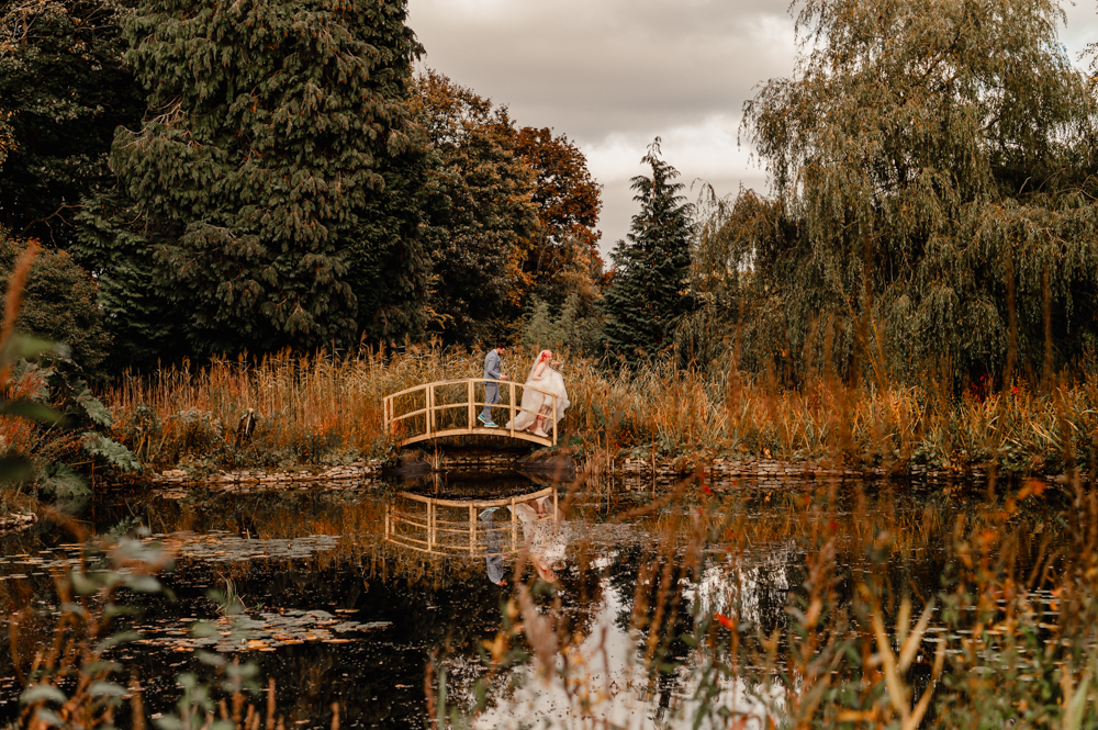 bride and groom on a bridge by a romantic pond dreamy countryside landscape
