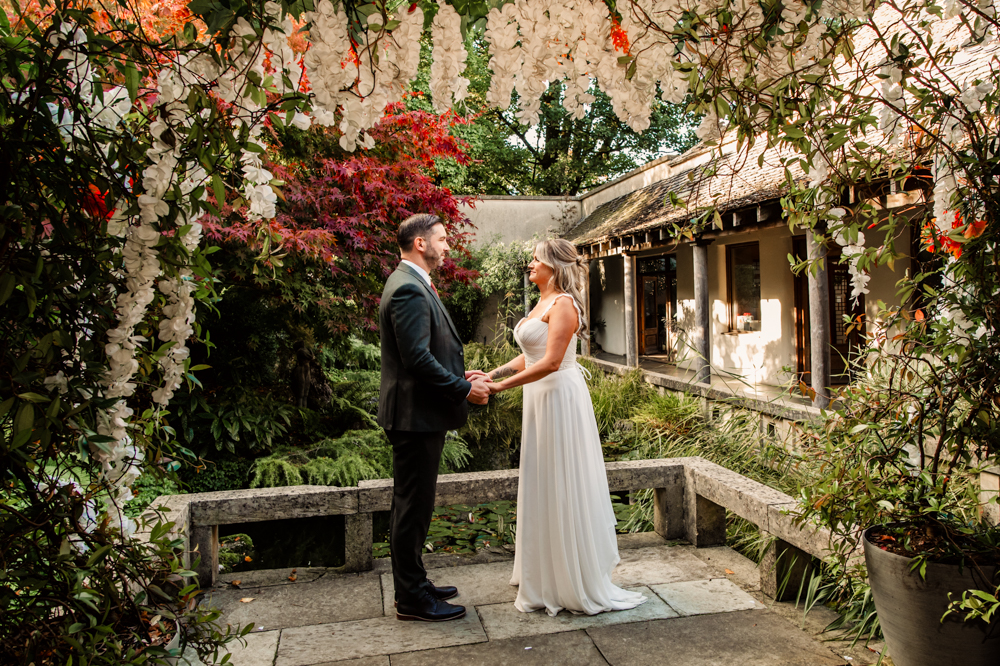 bride and groom getting married in a lush garden by the pond
