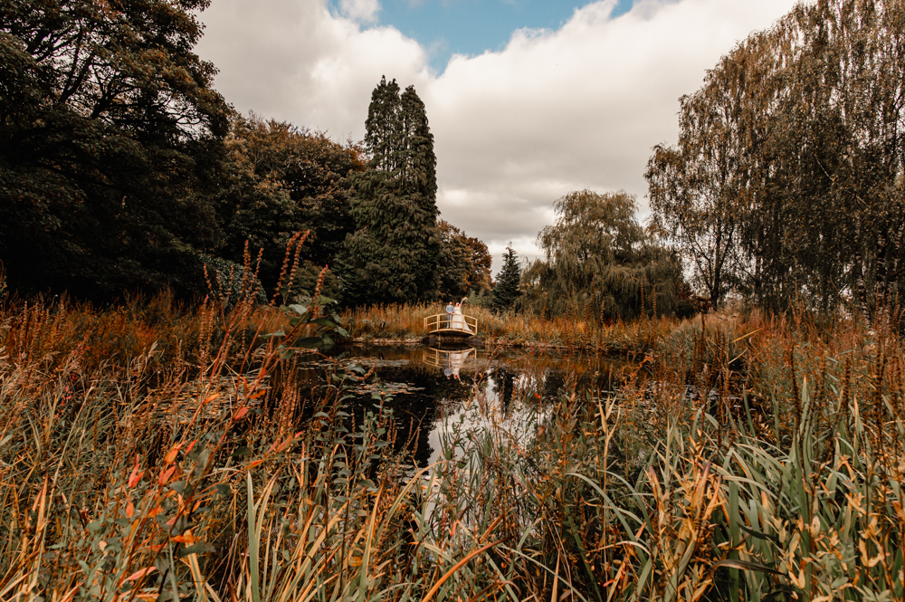 bride and groom on a bridge by a romantic pond