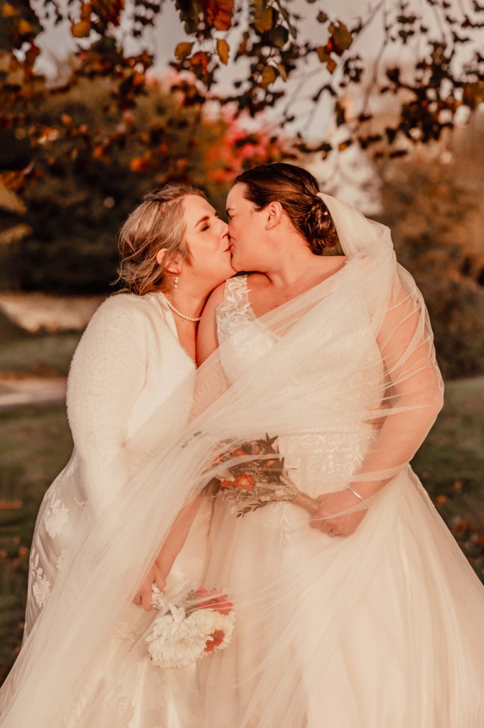 same sex couple kissing at sunset in the autumn stroud wedding