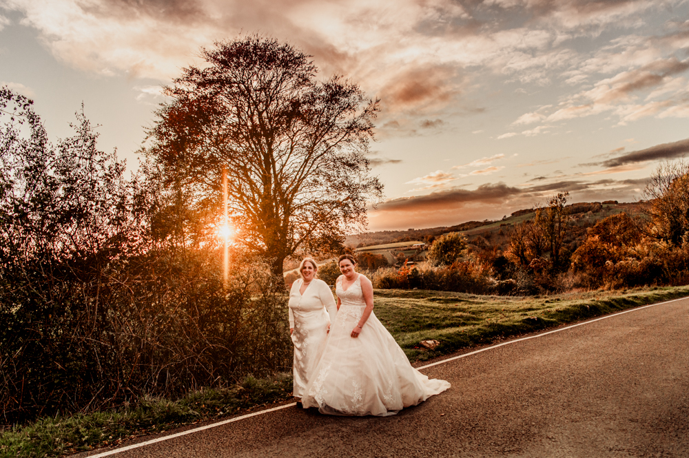 two brides walking in the countryside at sunset cotswolds wedding