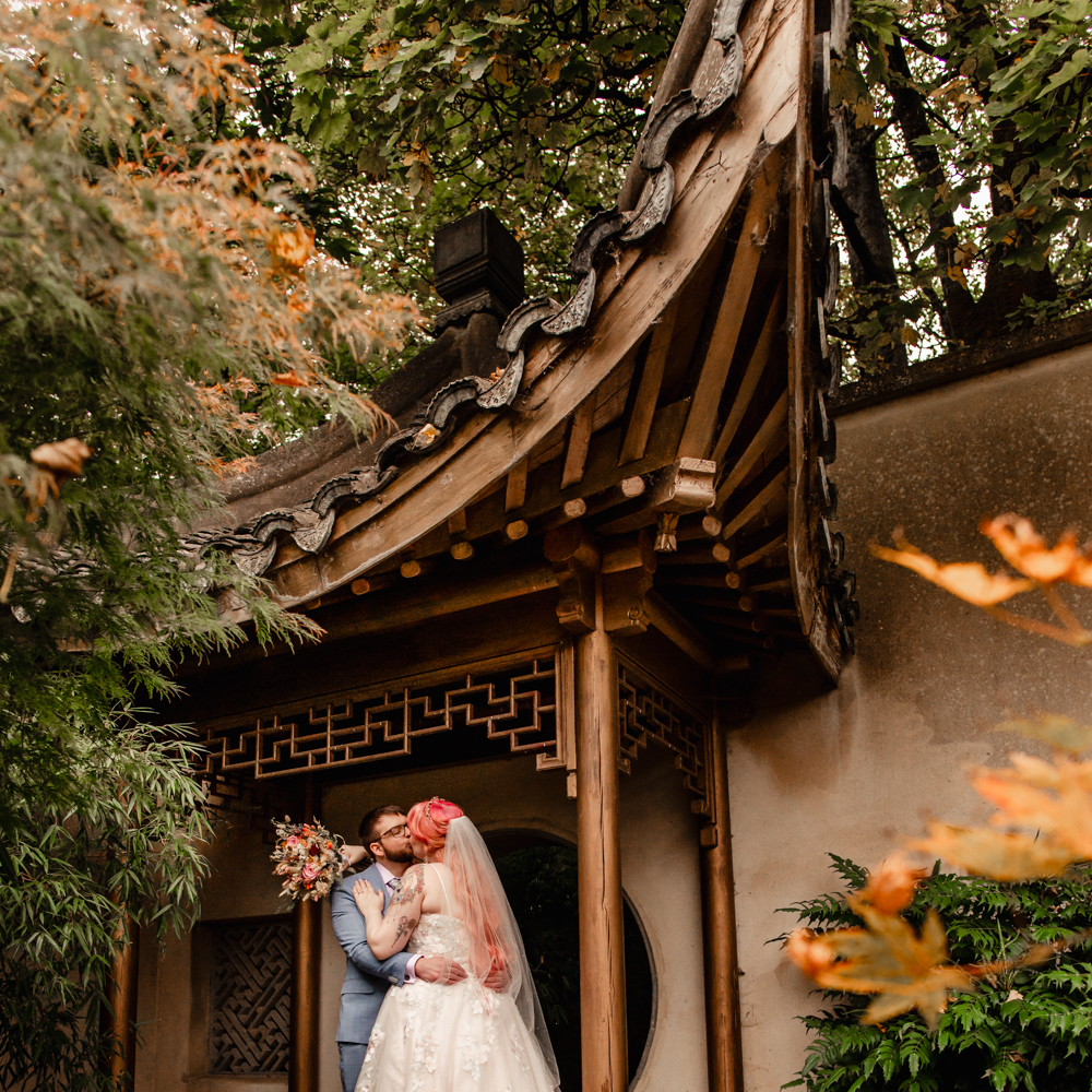 bride and groom kissing under asian arch at Matara centre cotswolds